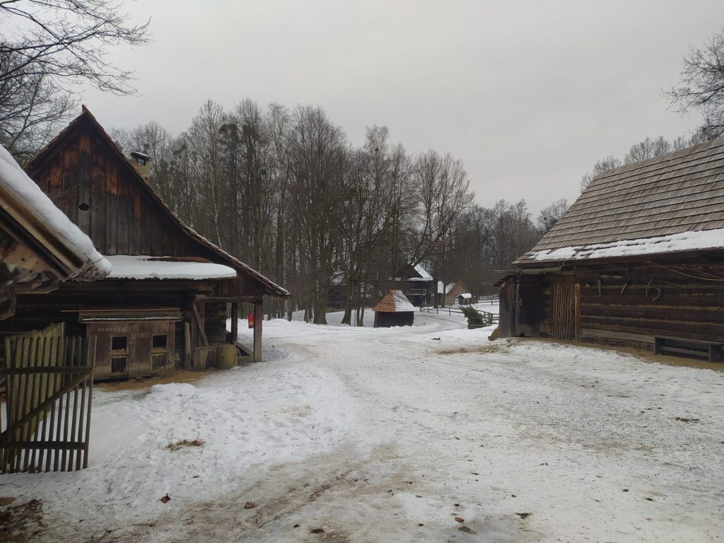 Záběr na nádvoří zasněžených chalup ve Valašské dědině v Rožnově pod Radhoštěm